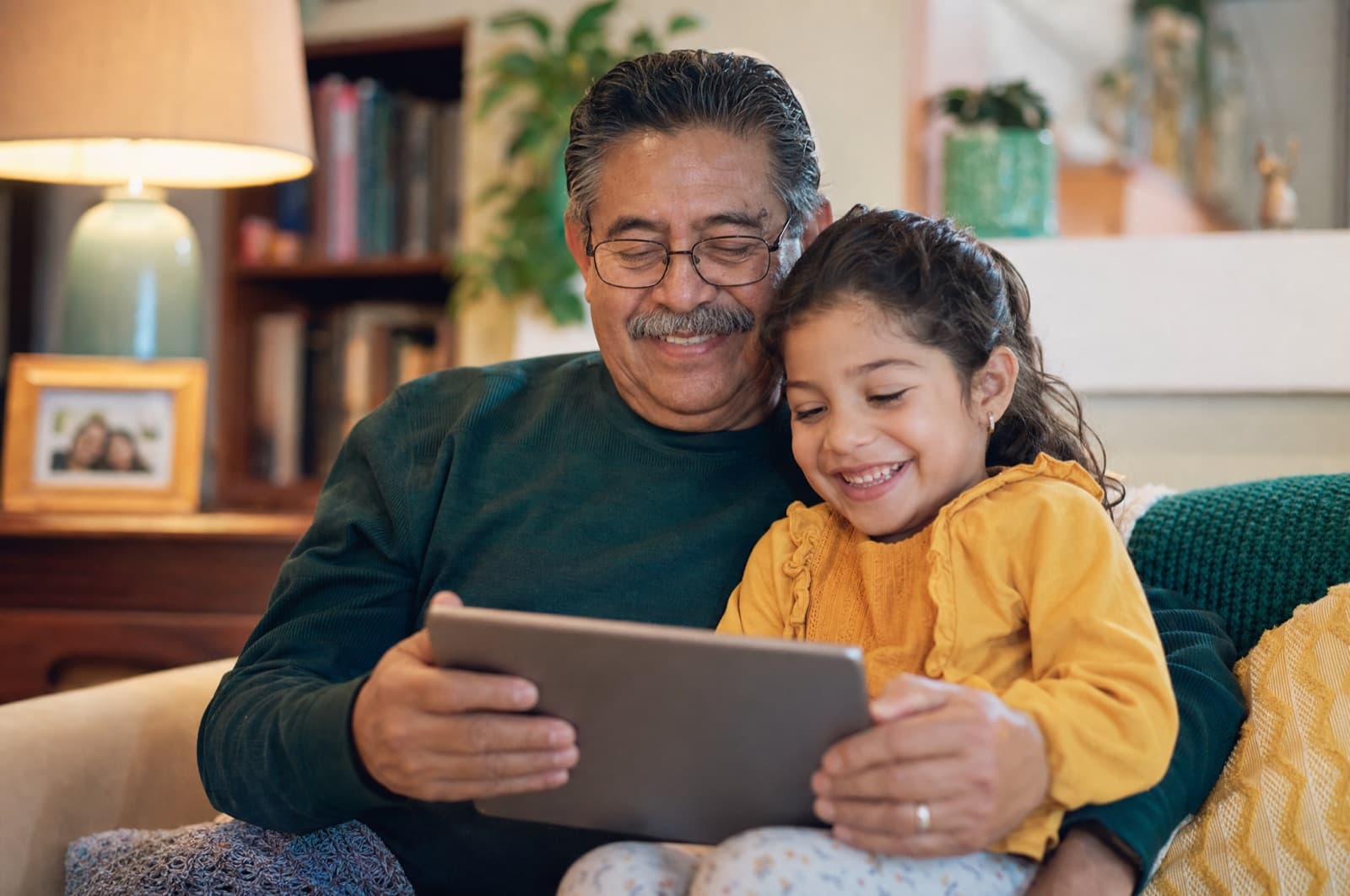 A grandfather and grandchild reading a story together on a tablet